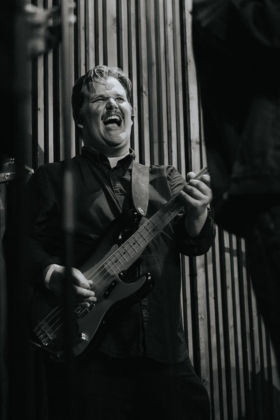 Frederick Midtstøl Groos ler mens han spiller bass på scenen